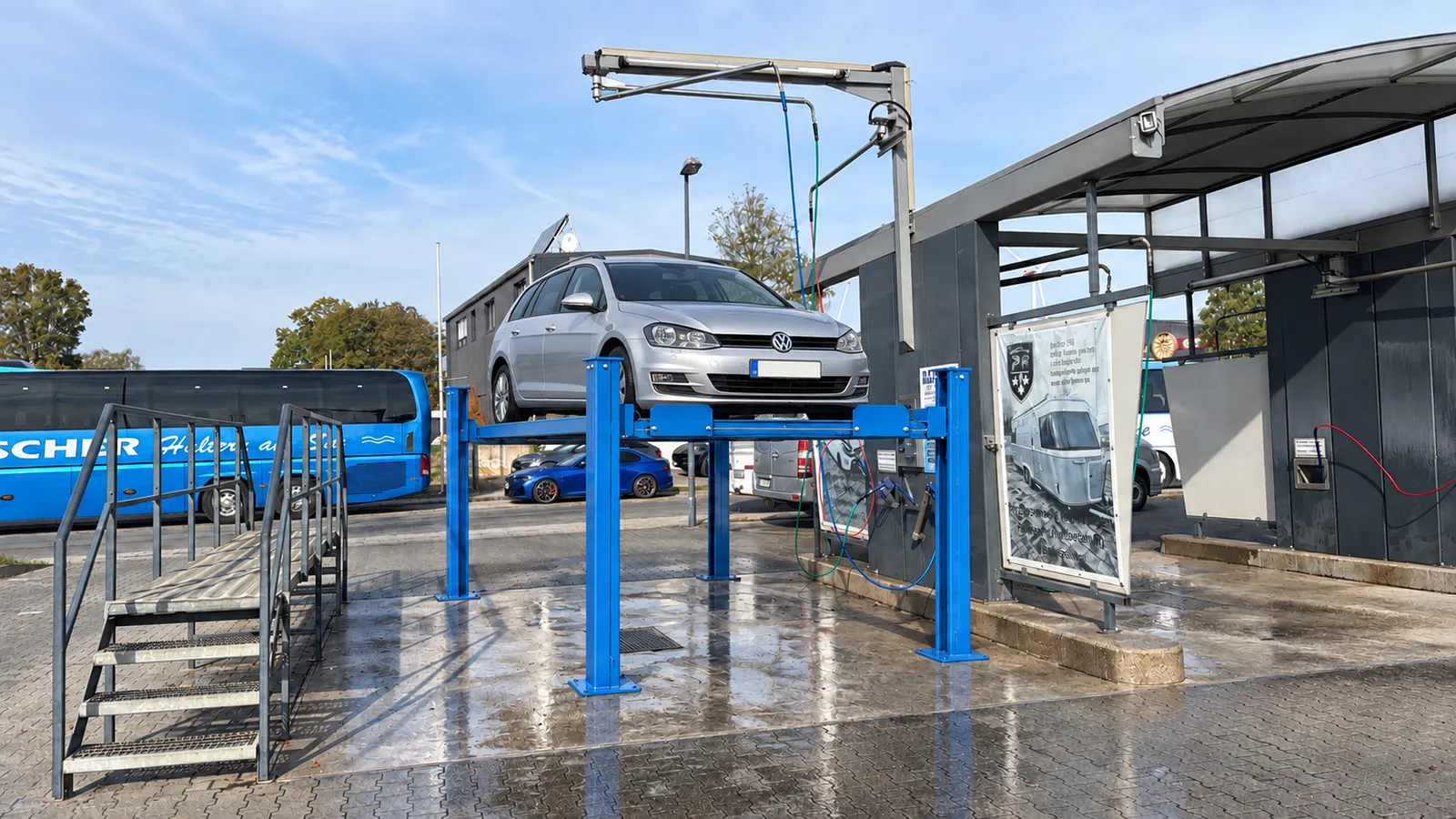 Silberner Kombi auf der blauen Vier-Säulen-Hebebühne in unserer offenen Waschbox